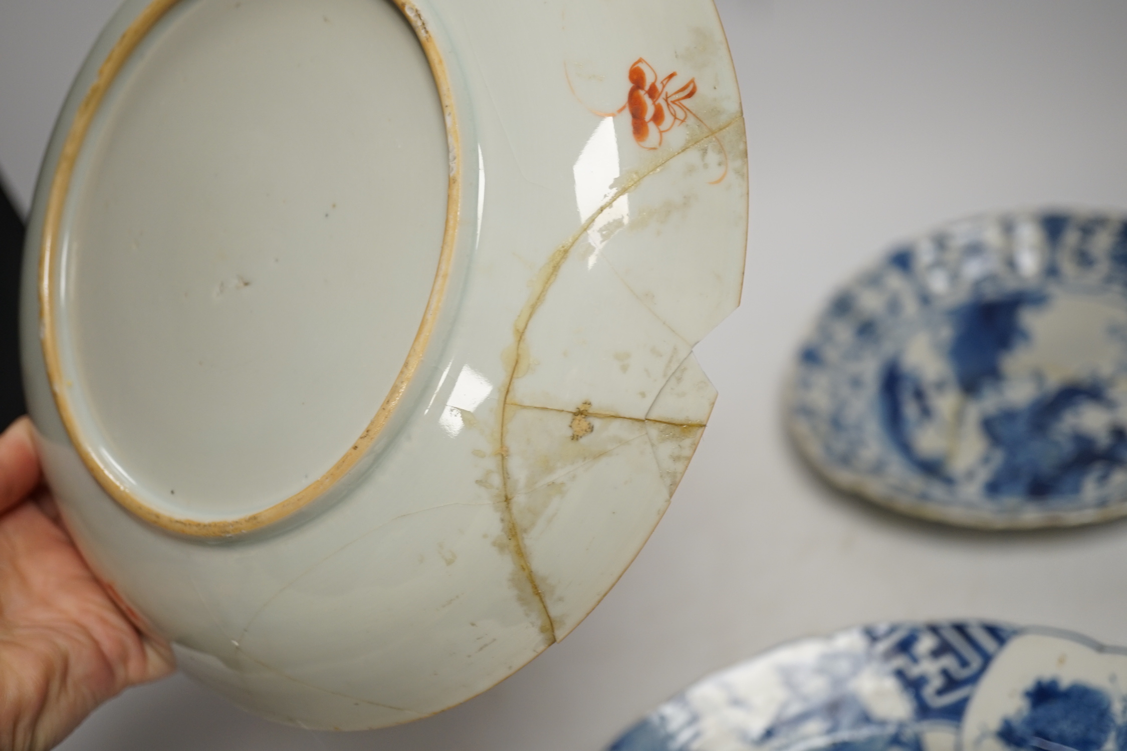 A Chinese blue and white ‘warriors’ bowl, Kangxi mark and period, a similar ‘hunting’ saucer dish, and a famille verte saucer dish, all Kangxi period (3), largest 27cm in diameter